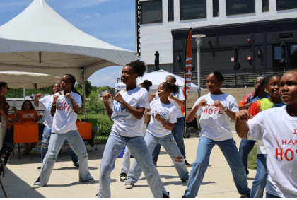 A group of children in white shirts joyfully dancing together in a lively setting