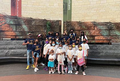 Children in vibrant masks gather closely, smiling for a joyful group photo