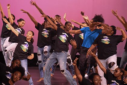 A vibrant group of young people engaged in a dance performance on stage, radiating excitement and creativity